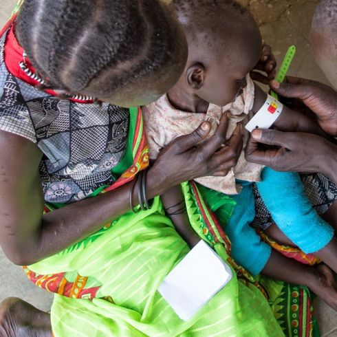 CARE-Gesundheitsexperten untersuchen Kinder auf Unterernährung mit der Hilfe von farbigen Papierbändern. (Foto: CARE/Dan Alder)