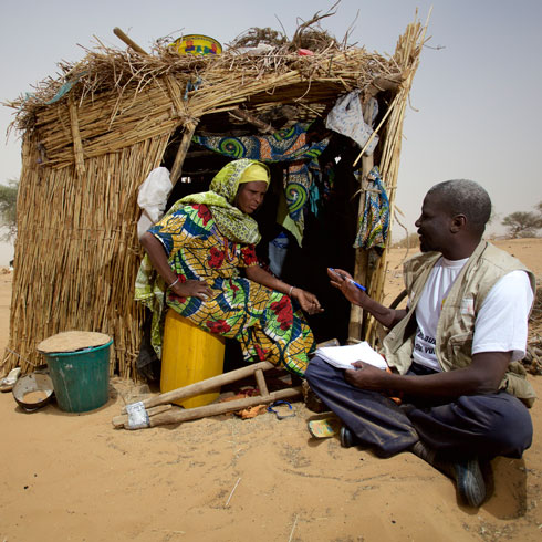 Un homme et une femme sont assis devant une maison en paille.