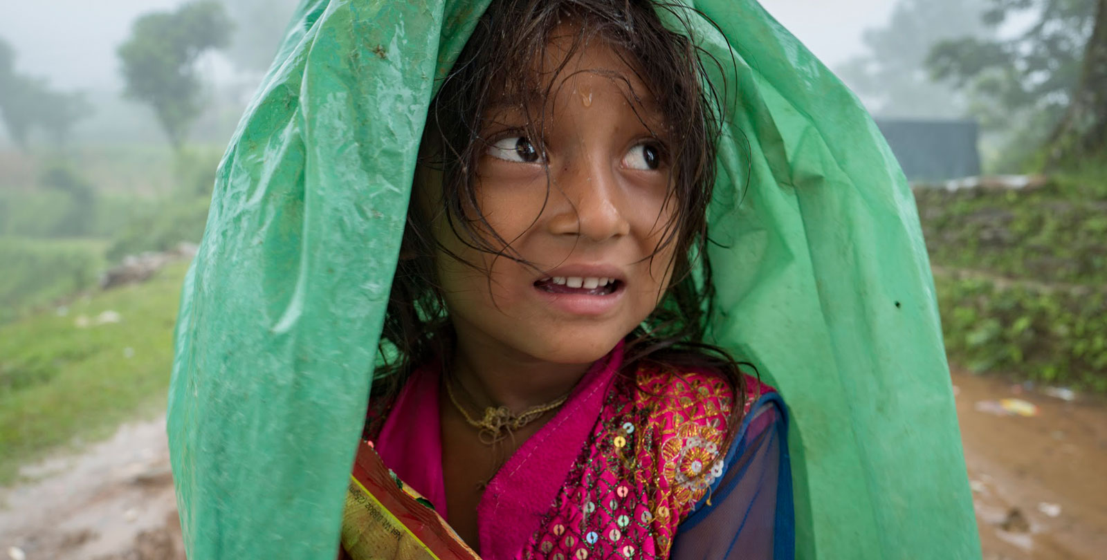 Ein nepalesisches Kind versucht sich nach der Erdbebenkatastrophe mit einer Plane vor dem Regen zu schützen.