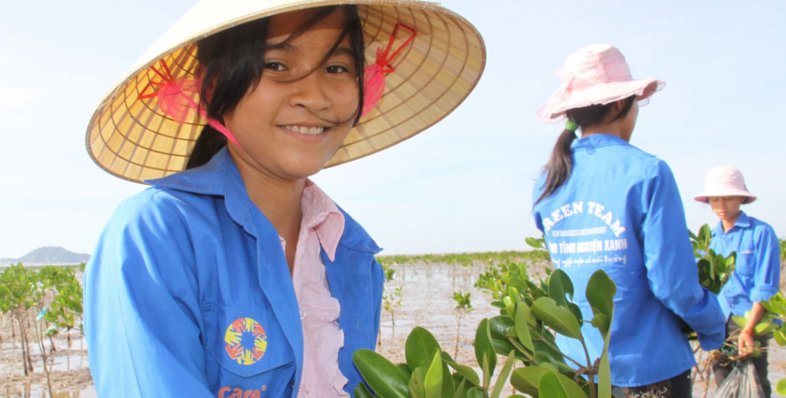 Reboisement: Des collaboratrices vietnamiennes de CARE sèment de nouvelles plantes sur un champs inondé. 