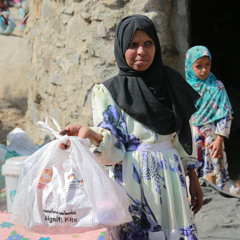 Une femme tient un sachet CARE dans la main.