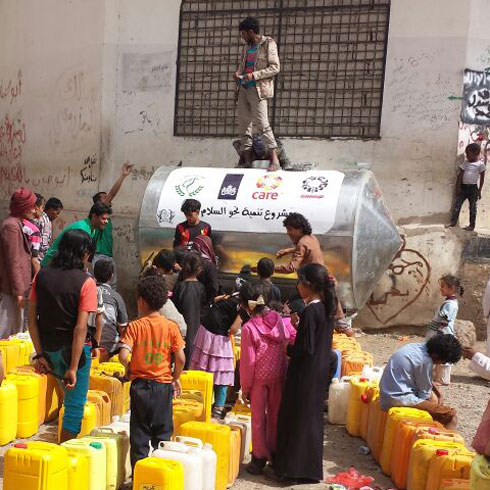 Un groupe se tient devant une cuve d'eau avec des jerricans.