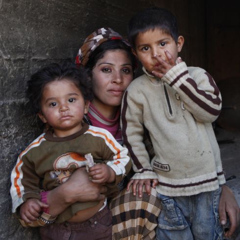 Deux enfants réfugiés sont assis sur les genoux de leur mère.