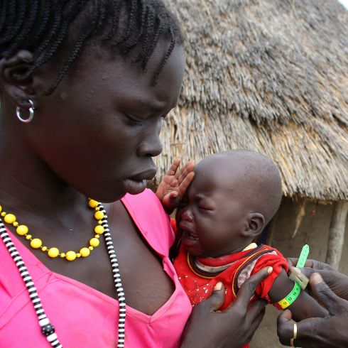 Une femme africaine porte son bébé qui pleure dans ses bras.