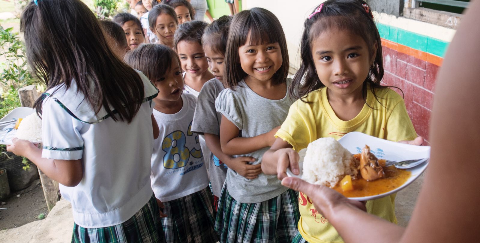 Des enfants aux philippines font la queue pour recevoir à manger